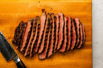 A steak on a cutting board with a knife.