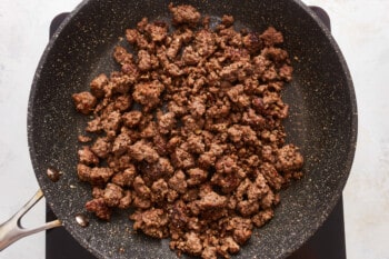 A frying pan with ground beef in it.