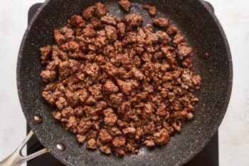 A frying pan with ground beef in it.