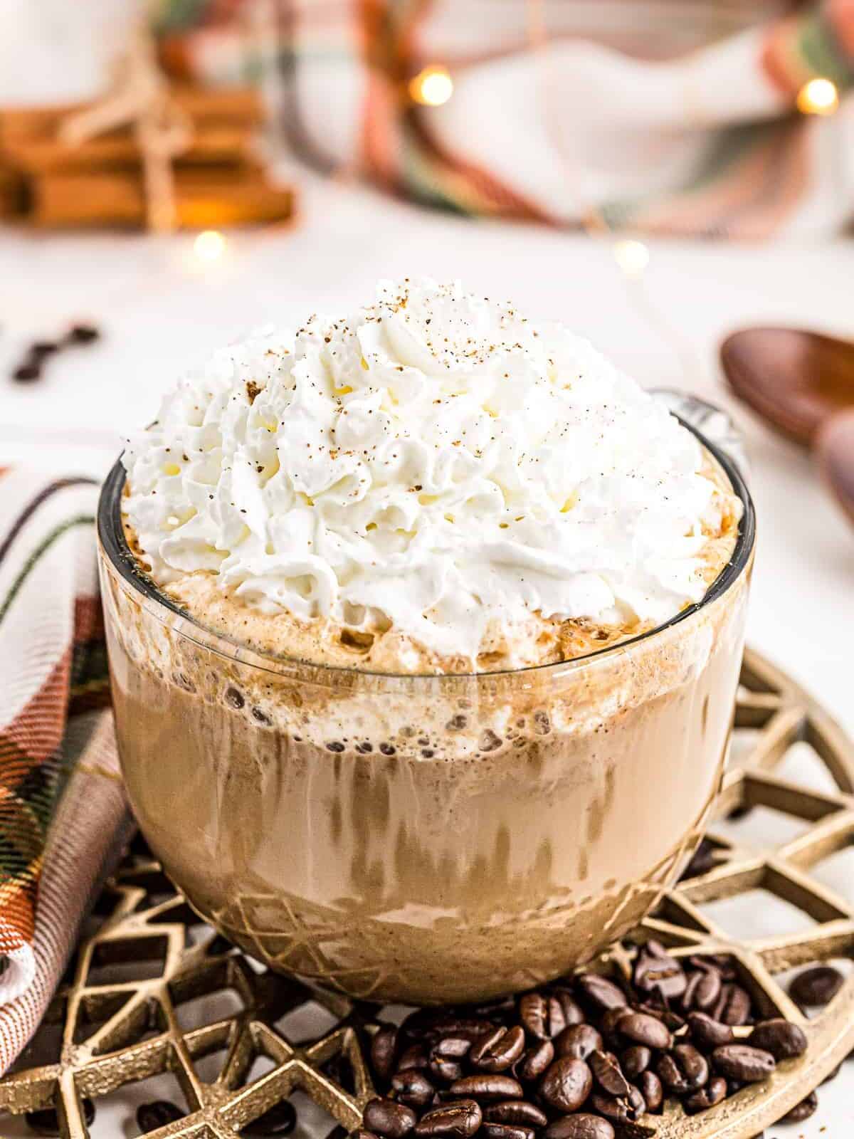 large clear mug of homemade pumpkin spice latte topped with whipped cream.