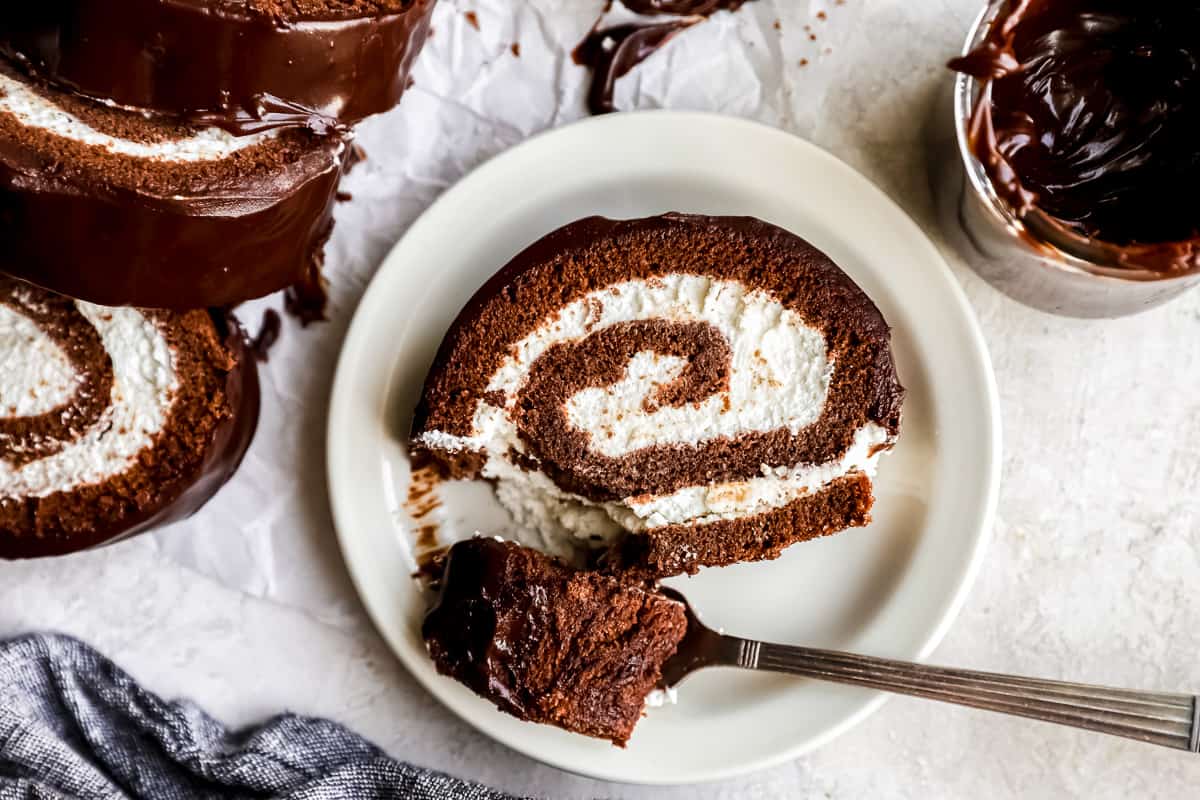 Overhead view of a partially eaten slice of swiss roll cake on a plate with a fork.