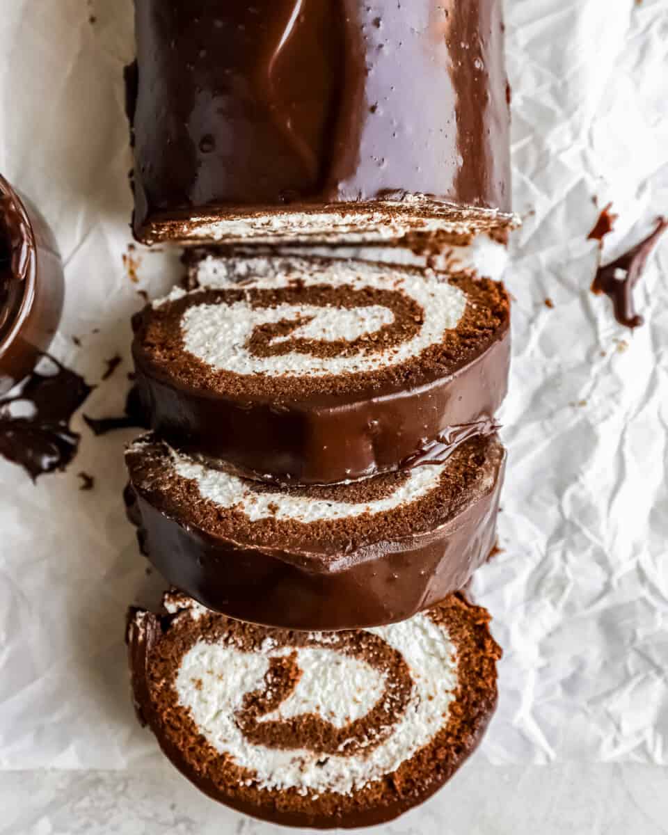 A slice of chocolate rolled cake on a piece of paper.