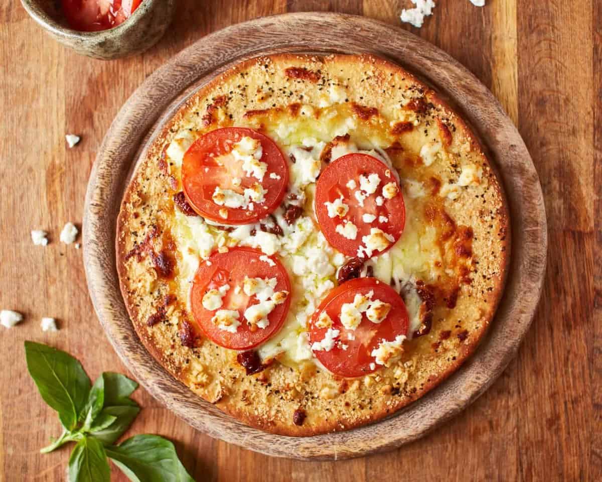 overhead view of white pizza on a round wooden cutting board.