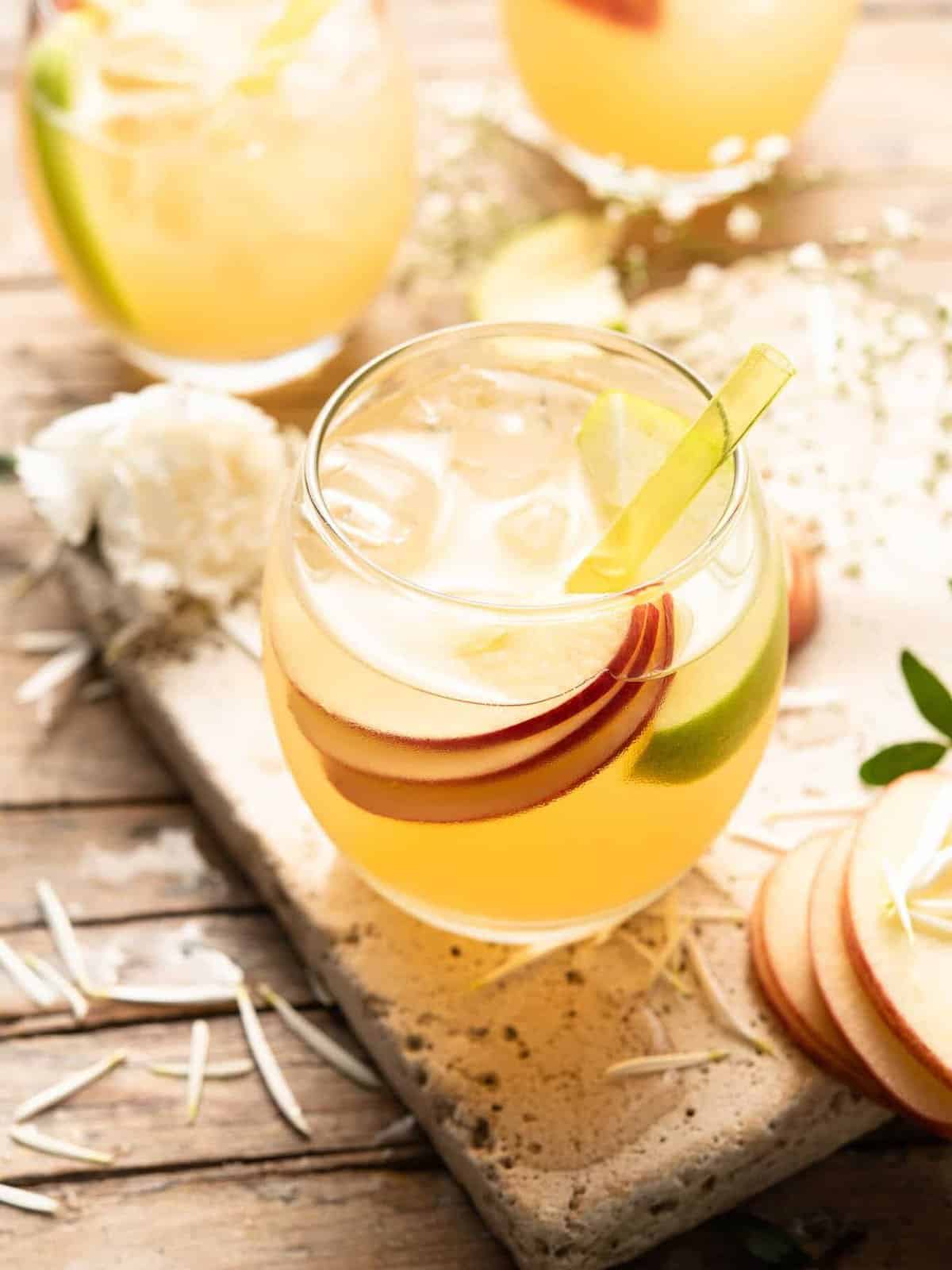 A refreshing apple pie drink garnished with slices of apples and sprigs of thyme.