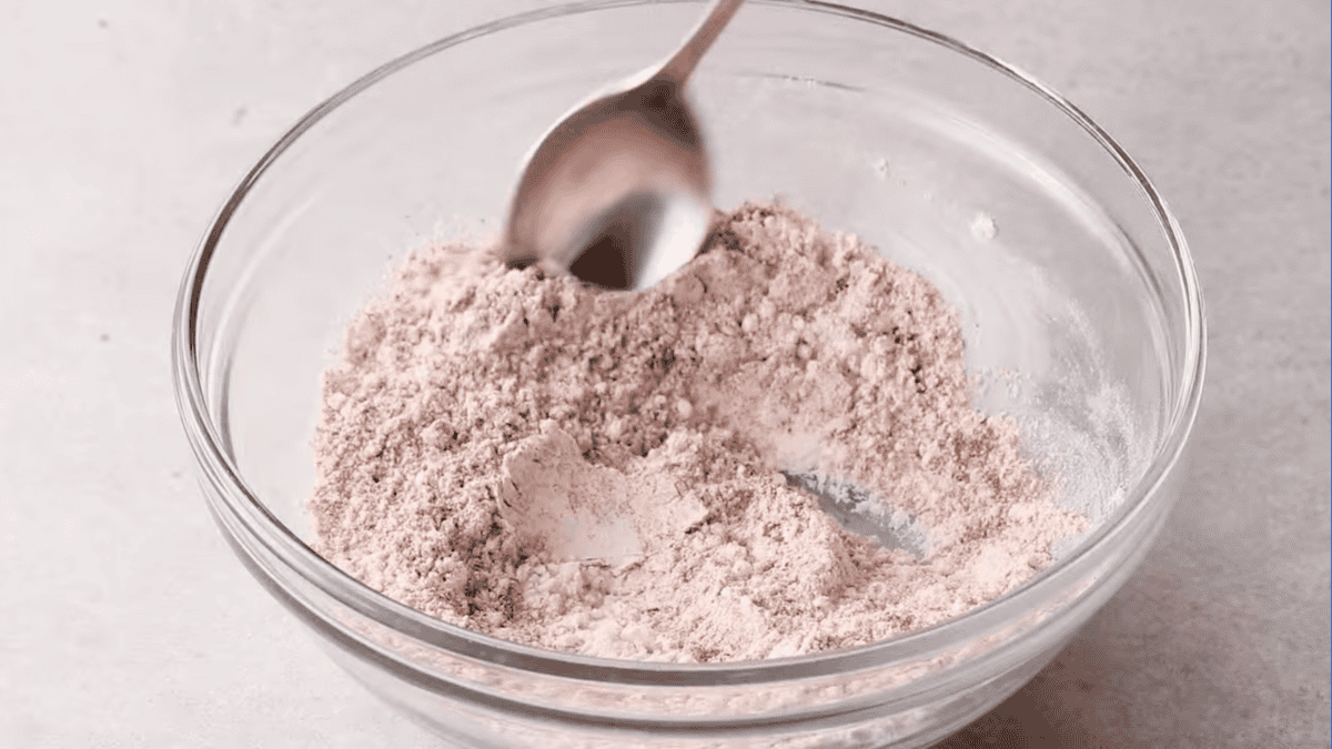 mixing spices and flour in a glass bowl with a spoon.