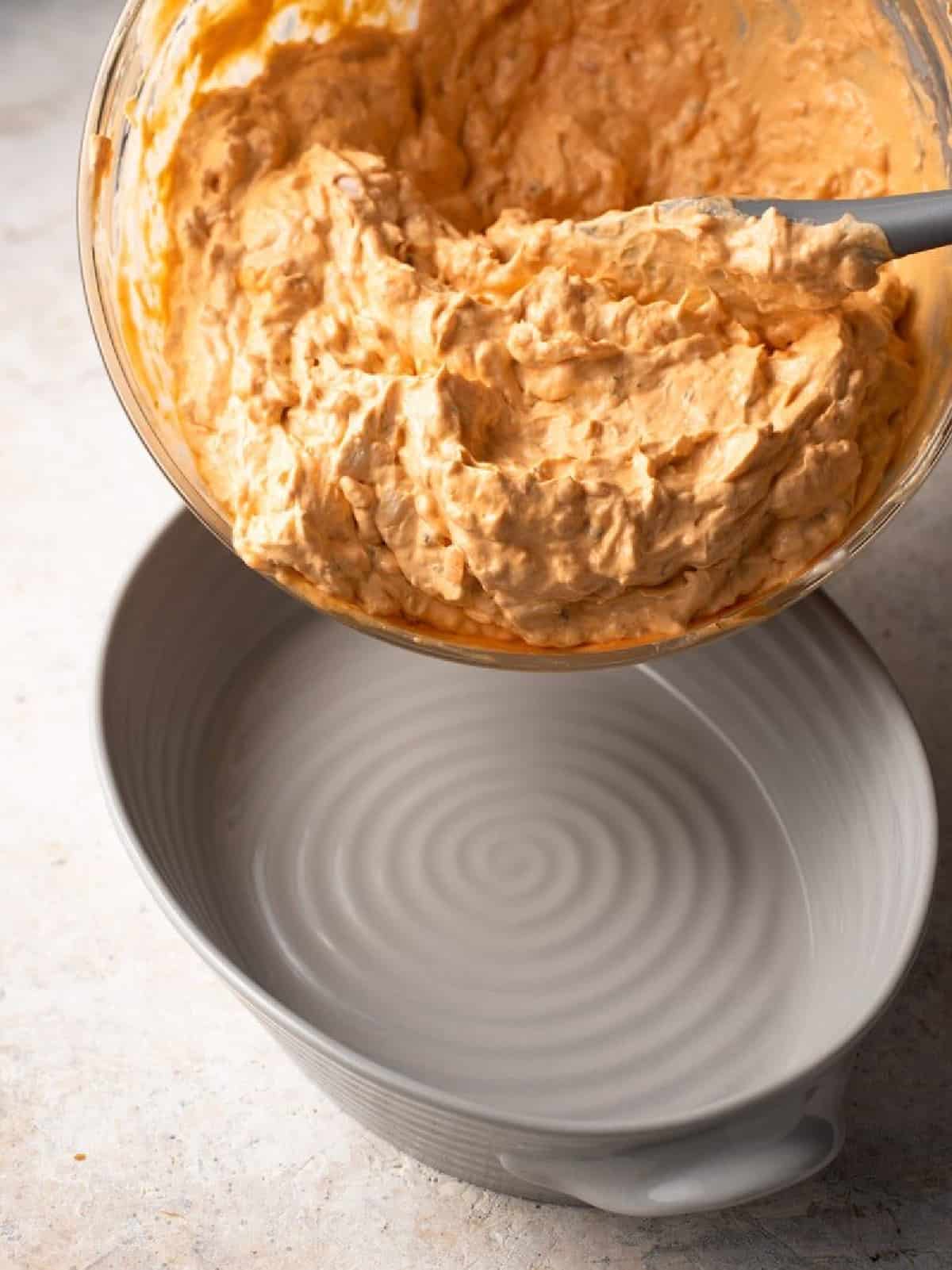 pouring buffalo chicken dip mixture into casserole dish