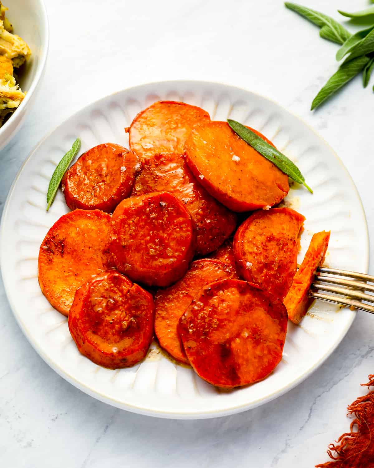 A plate of candy yams with a fork next to it.