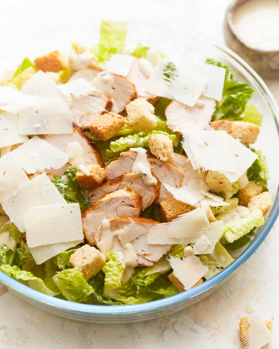 A bowl of chicken caesar salad with croutons and parmesan.