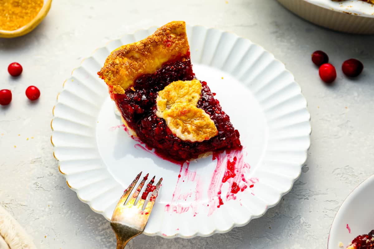 A slice of cranberry pie on a plate with a fork.