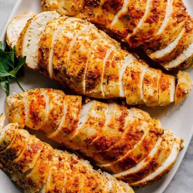 overhead sliced crockpot chicken breasts with spice rub on white plate