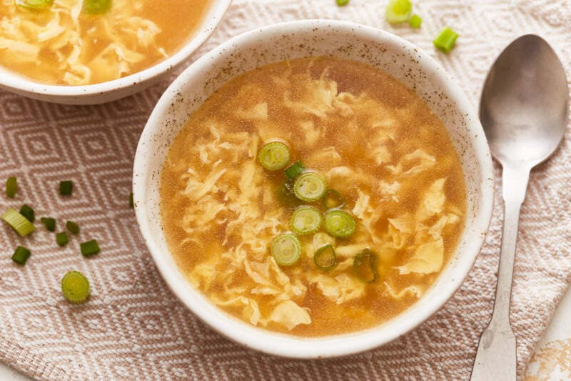 Two bowls of soup with noodles and green onions.