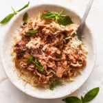 A white bowl with rice and meat in it.