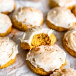 Pumpkin cookies with icing and a bite taken out.