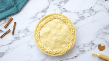 sugar sprinkled over apple pie covered with a top crust with a braid detail.