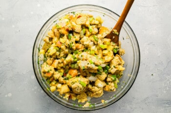 A bowl of chicken salad with a wooden spoon.