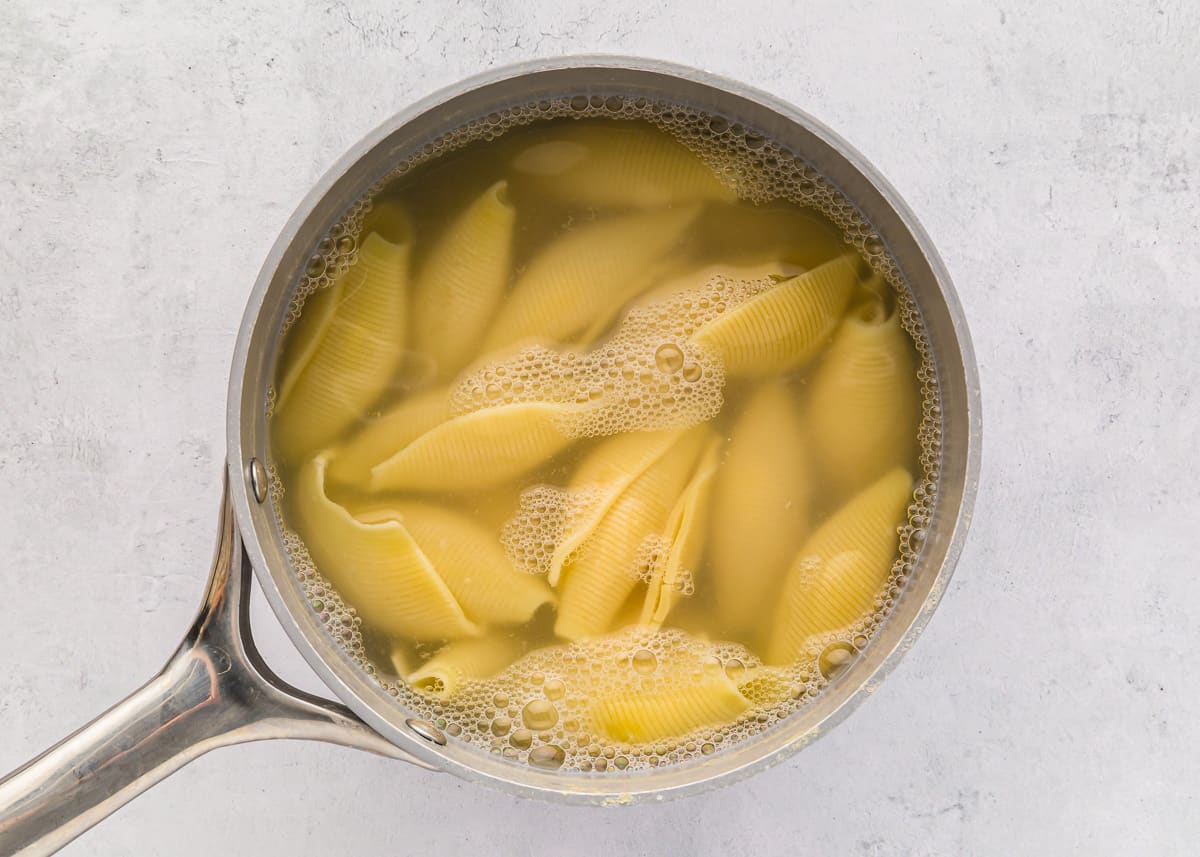 Jumbo pasta shells boiling in a pot of water.