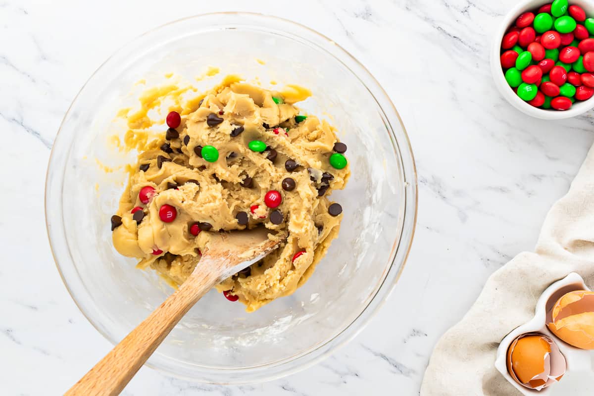 A bowl of cookie dough with chocolate chips and m&m's.