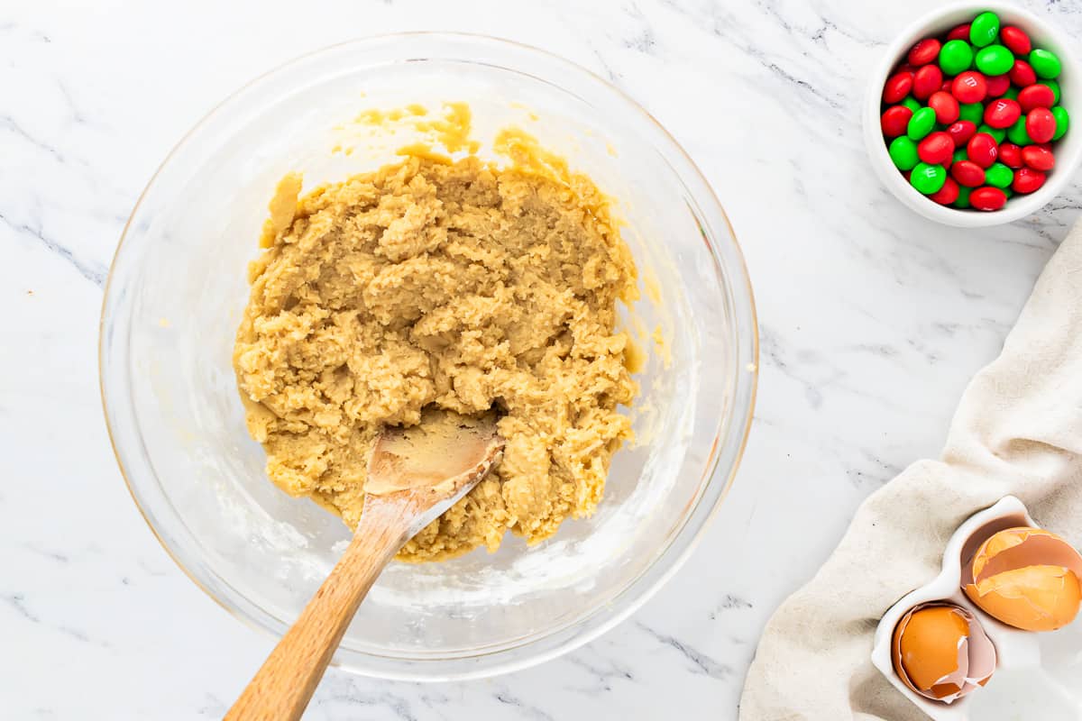 A bowl of cookie dough with a wooden spoon next to it.