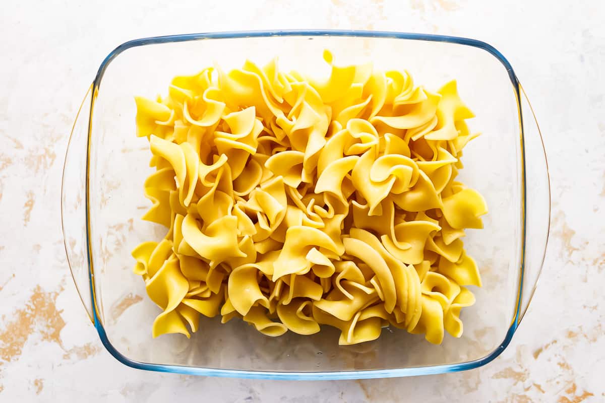 Penne pasta in a glass bowl on a marble surface.