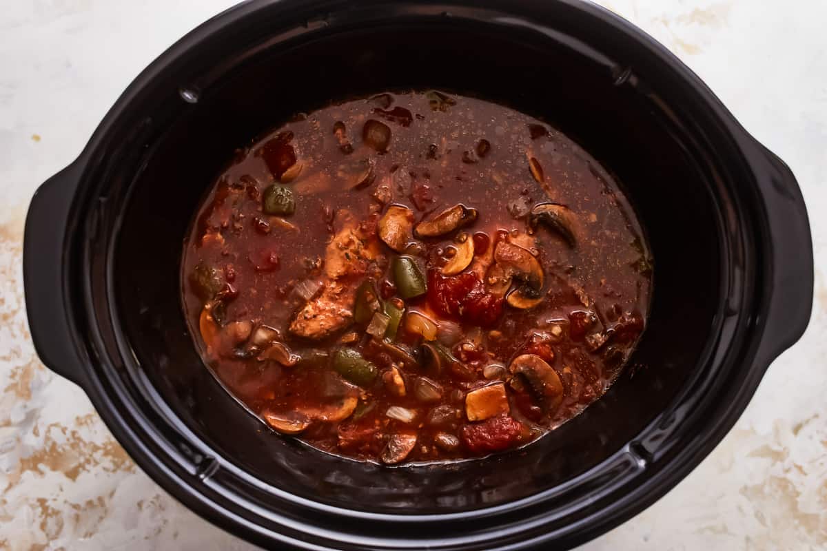 A crock pot full of chicken and mushroom stew.