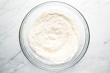 Flour in a glass bowl on a marble table.