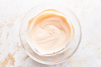 Whipped cream in a glass bowl on a white background.