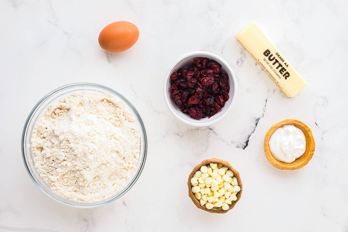 cookie mix, cranberries, white chocolate chips, an egg, a stick of butter, and some sour cream in individual bowls.