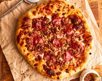 A meat lovers pizza on parchment paper.