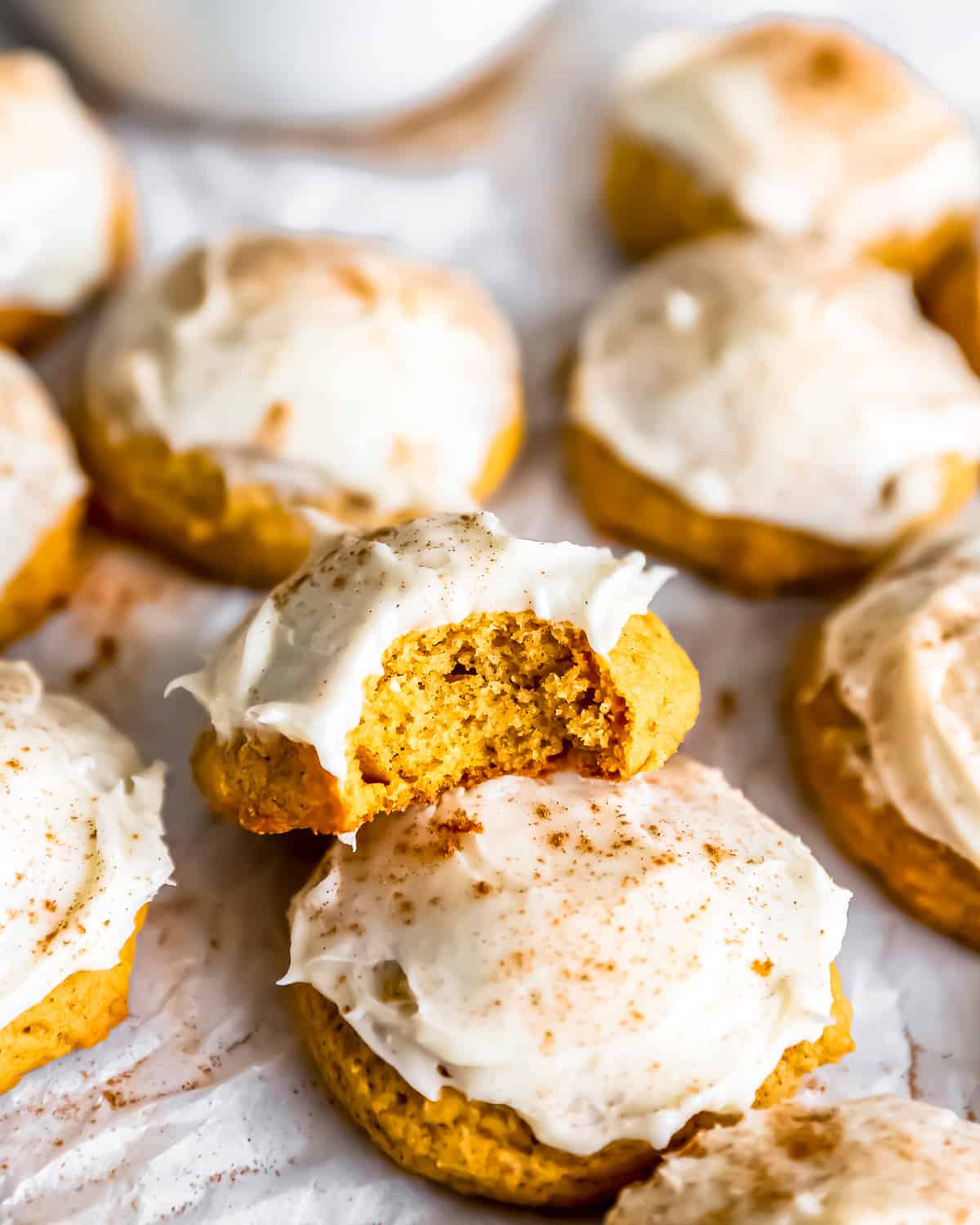 Pumpkin cookies with cream cheese icing and a bite taken out.