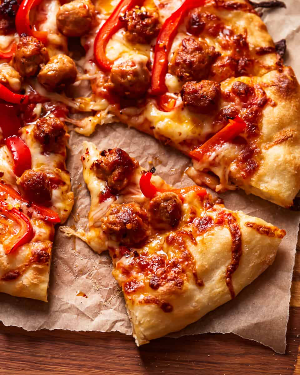 An Italian sausage pizza on a wooden board.