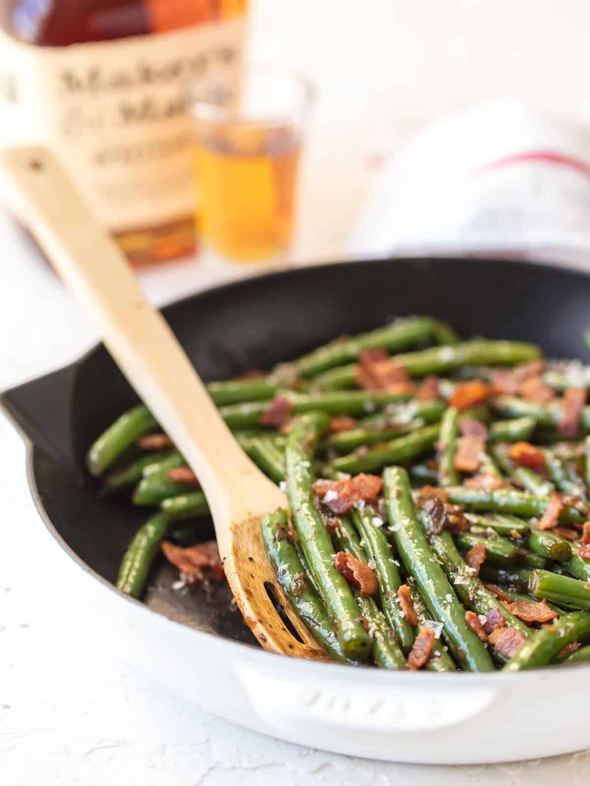 green beans with bacon cooking in a skillet.