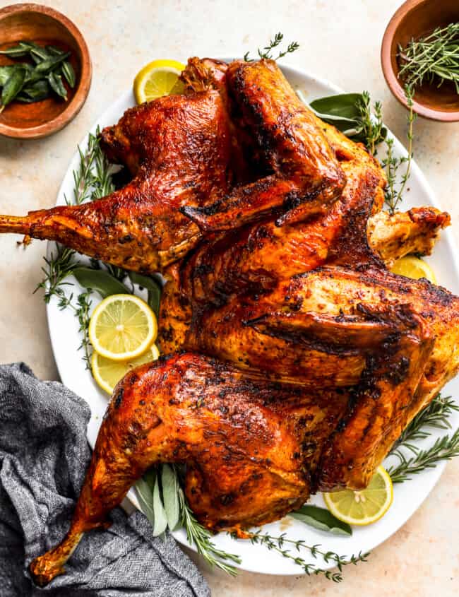 A roasted turkey on a plate with lemons and sprigs of thyme.