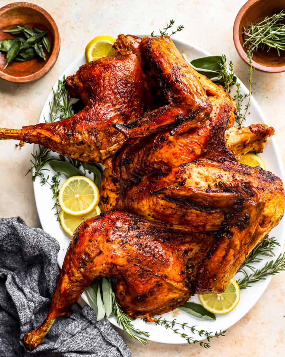 A roasted turkey on a plate with lemons and sprigs of thyme.