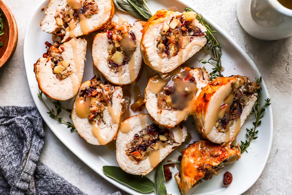 Turkey stuffed with cranberries and sage on a white plate.