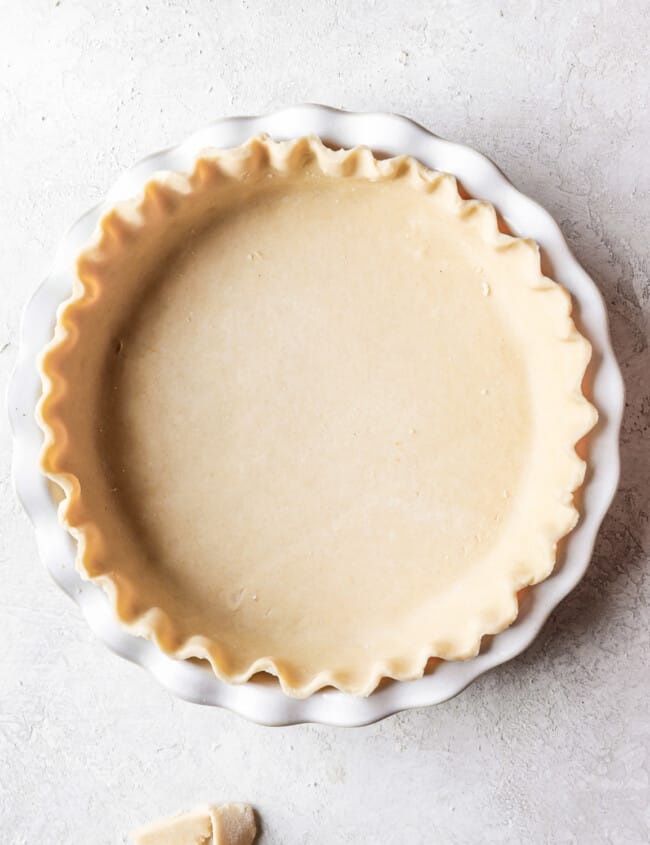 A pie crust in a white pie plate.