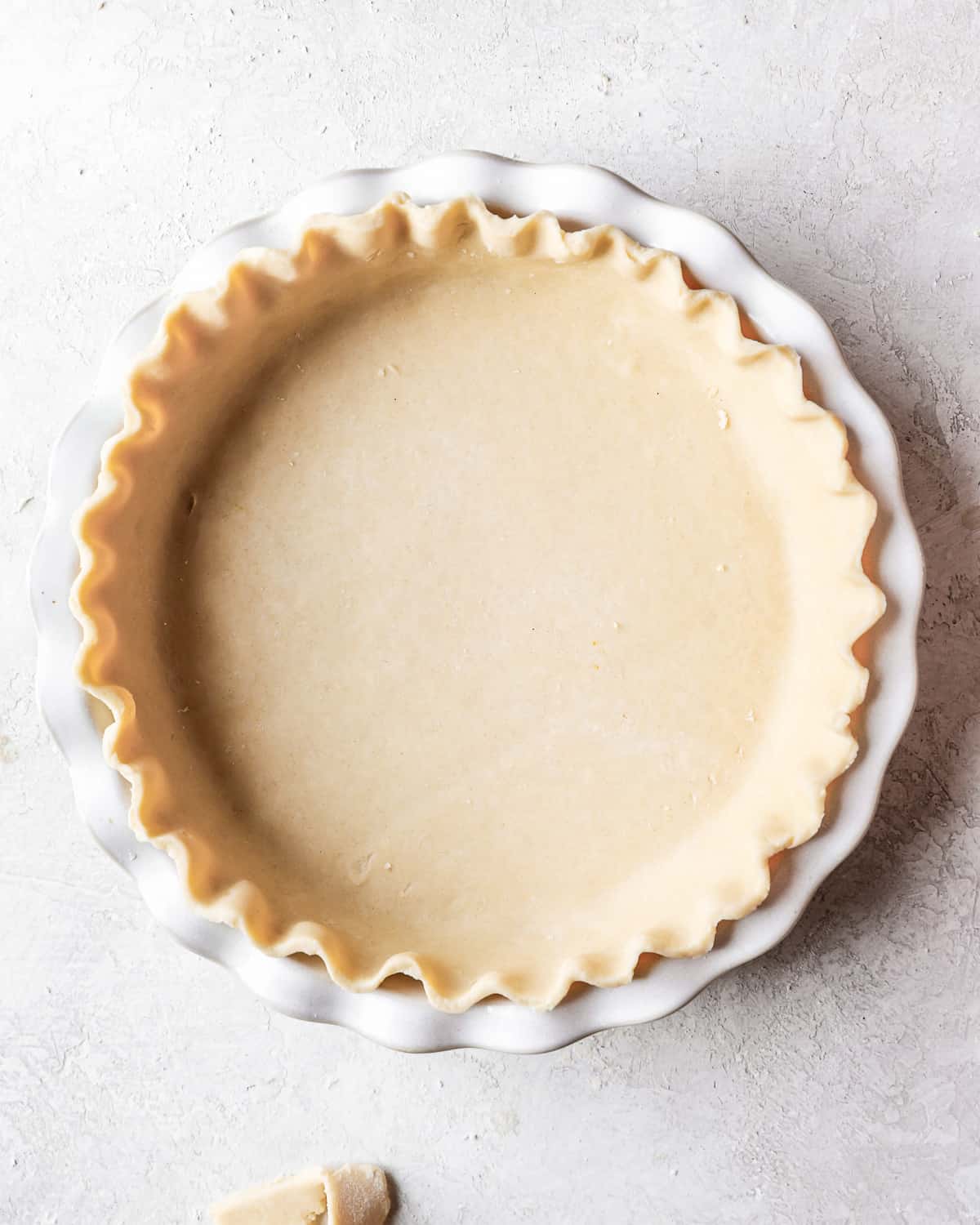 A pie crust in a white pie plate.