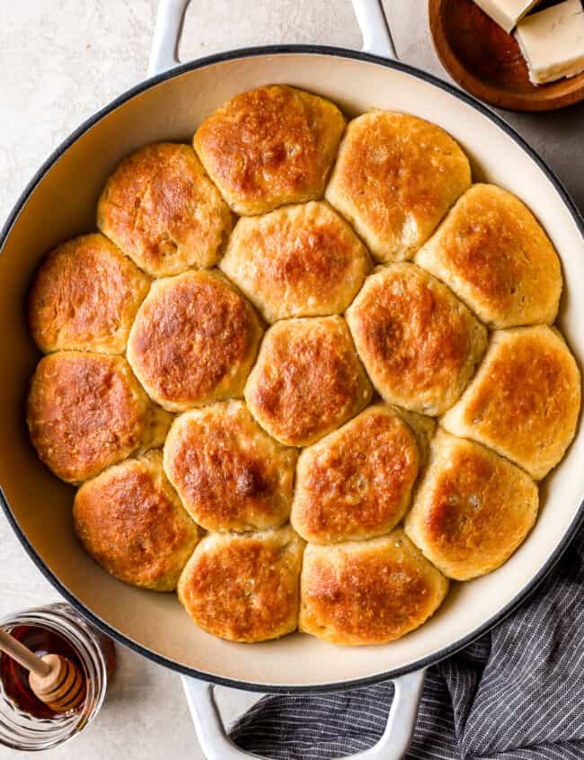 A skillet filled with biscuits and honey.