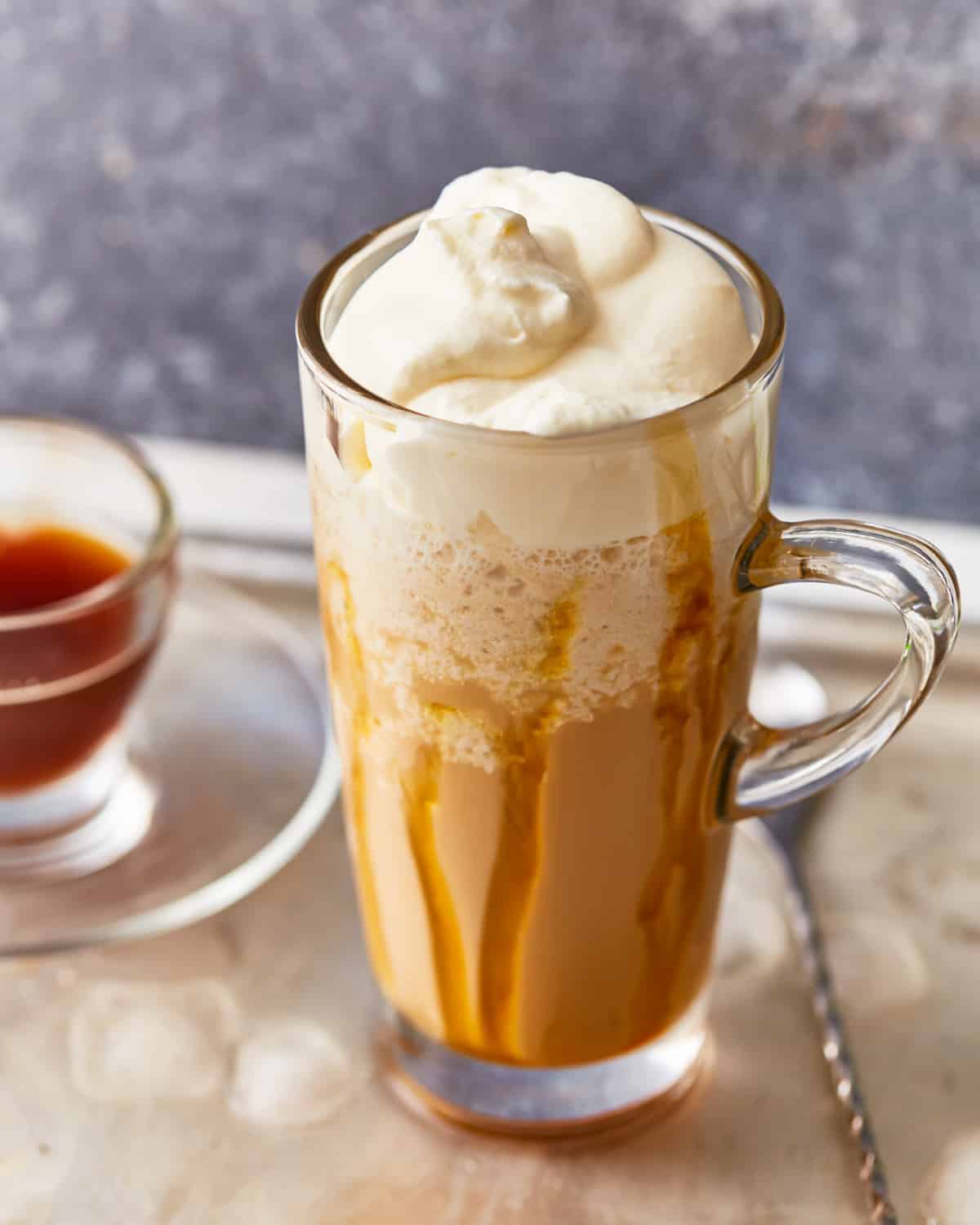 Blended coffee drink in a clear glass, drizzled with caramel and topped with whipped cream.