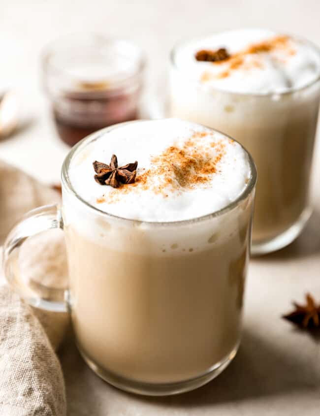 Two mugs of latte with cinnamon and star anise.