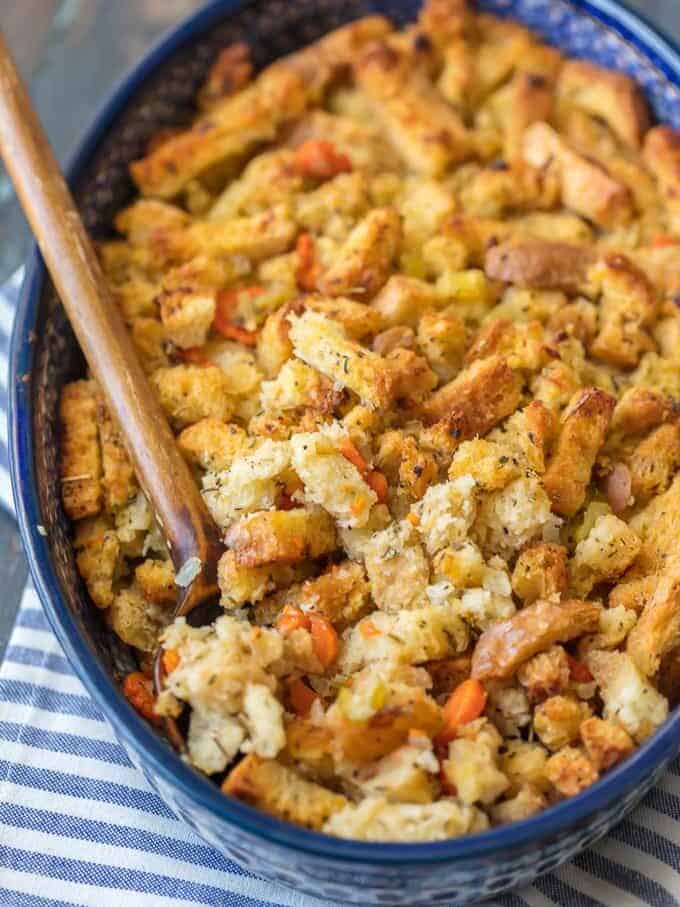 turkey stuffing in a blue baking dish with a wooden spoon.