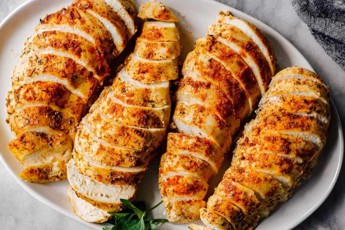 overhead sliced crockpot chicken breasts with spice rub on white plate