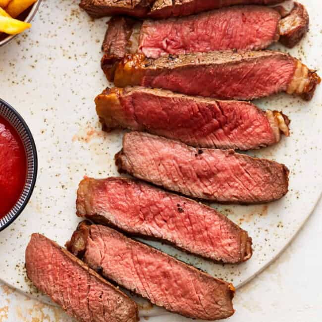 Steak with ketchup and fries on a plate.