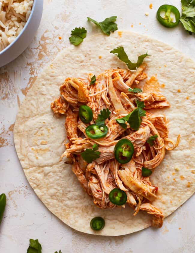 instant pot shredded chicken spread onto a tortilla to make tacos.