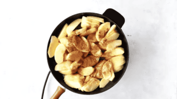 apple slices covered with cinnamon in a skillet.