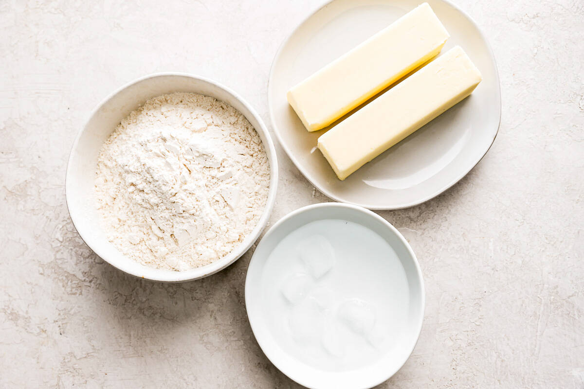 A bowl of flour, butter and sugar on a table.