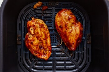 Two chicken breasts in an air fryer.