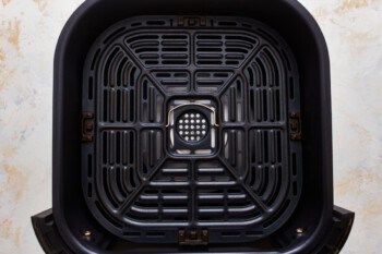 A close up of a black trash can on a white background.