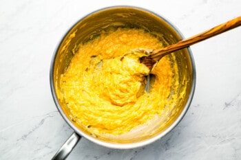 A pan full of yellow batter with a wooden spoon.