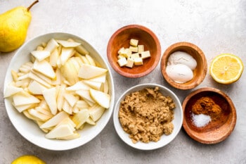 A bowl of pears, lemons, and other ingredients on a table.