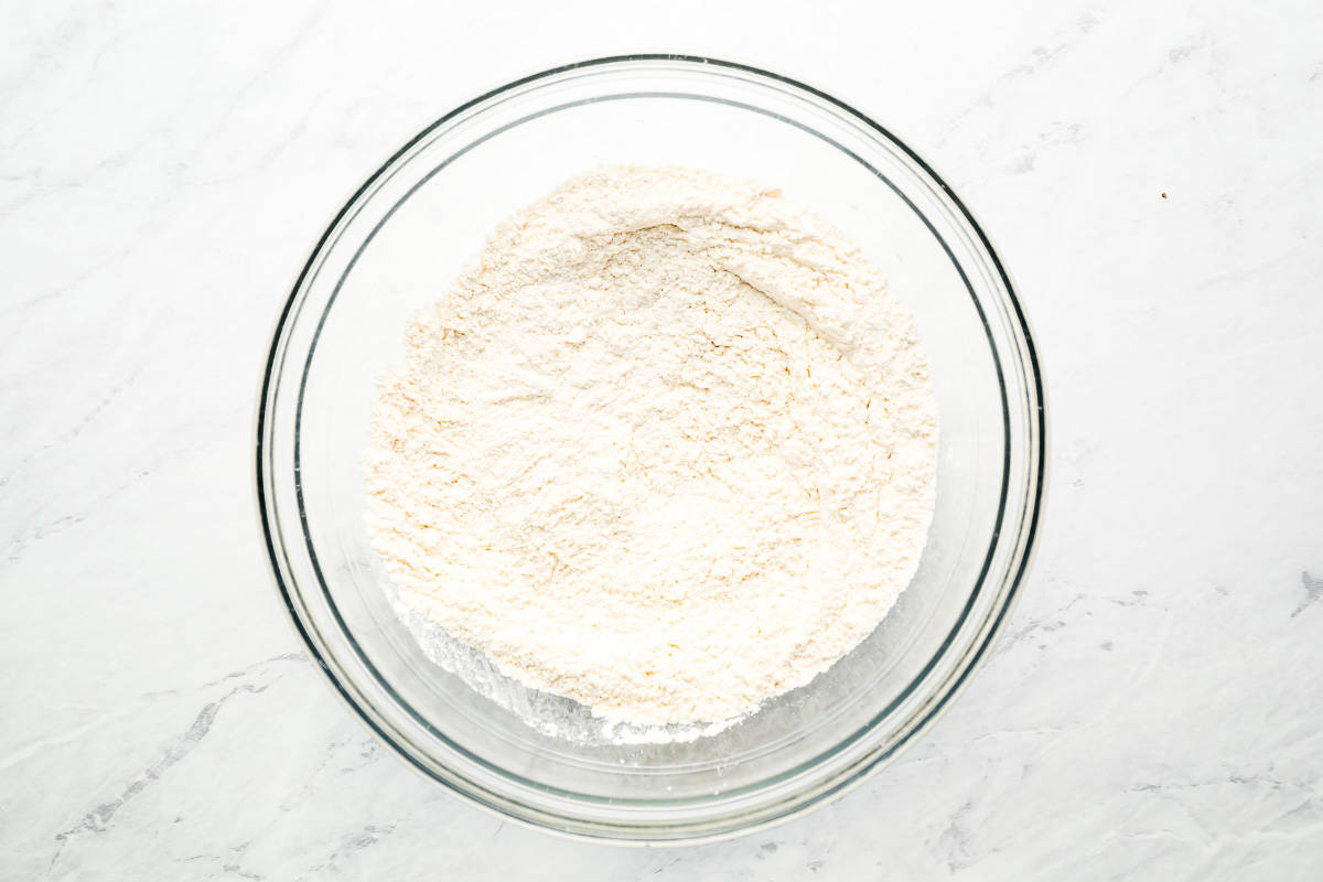 Flour in a glass bowl on a marble table.